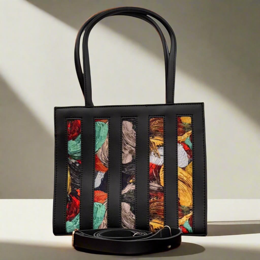 Black handbag with colorful abstract pattern on a wooden surface
